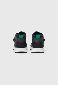 Baskets montantes noires et bleues avec des panneaux latéraux texturés et un accent vert contrastant au niveau du talon, avec une semelle blanche.