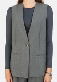 Grå, ärmlös väst med platt krage, en knapp och två framfickor. Tillverkad av texturerad tyg med en skräddarsydd passform.