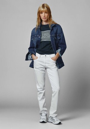 Chaqueta de mezclilla sobre una camiseta negra con texto gris, jeans blancos y zapatillas grises. El conjunto presenta un corte relajado y un diseño clásico.