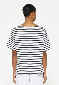 Camiseta de rayas en blanco y negro, de manga corta y escote barco, con un corte holgado y textura de algodón suave.