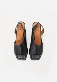 Sandales slingback en cuir noir avec des orteils carrés et des sangles arrière élastiques, semelles intérieures beige, vues de dessus sur un fond blanc.
