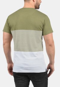 Camiseta de algodón verde oliva con panel de franjas horizontales en blanco y oliva. Manga corta, cuello redondo, corte regular, textura ligera.