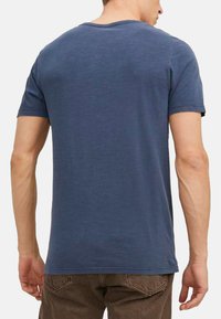 T-shirt blu a maniche corte con scollatura rotonda, realizzato in un materiale morbido, con una texture leggermente sbiadita. Nessun motivo o accento visibile.