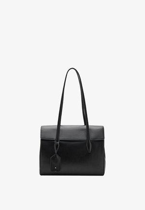 Bolso de piel negra con forma estructurada, textura suave, asas cortas y una etiqueta extraíble. Diseño sencillo sin herrajes visibles.