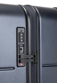 Valise rigide avec une finition bleu marine foncé, dotée d'une serrure à combinaison, d'une serrure TSA et de fermetures éclair doubles. Texture lisse et conception durable.