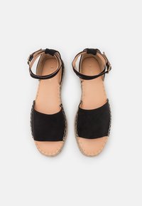 Černé semišové espadrilové sandály s řemínkem kolem kotníku, hnědou koženou stélkou a jutovou podešví se dekoračním šitím.