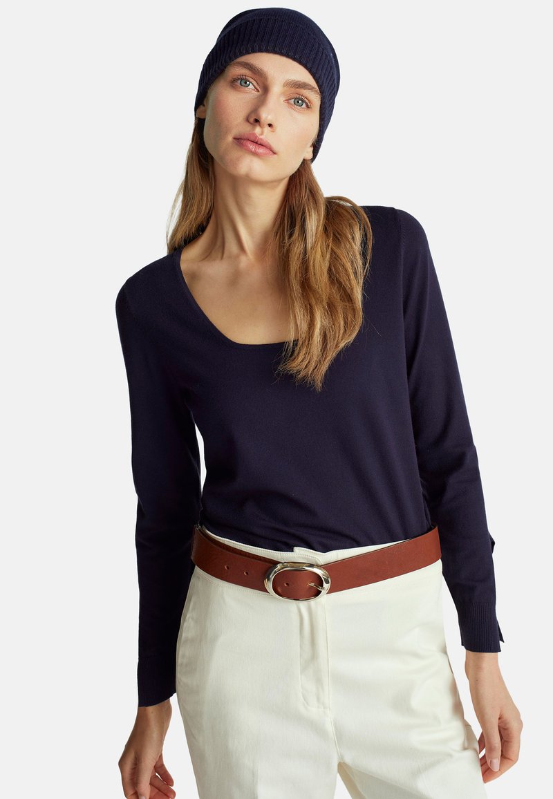 Námořnický modrý dlouhý rukáv s výstřihem do lodičky, spárovaný se světlými kalhotami. Hnědý pásek s kulatou stříbrnou sponou. Na hlavě je uháčkovaná námořnická modrá čepice.