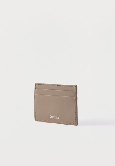 Λεπτή θήκη καρτών από δέρμα ταουπέ με δύο θήκες καρτών και το λογότυπο "Off-White" ανάγλυφο σε λευκό στην κάτω δεξιά πλευρά μπροστά.