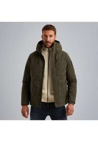 Maslinasto zelena jakna s kapuljačom, zatvaranjem na zip i dugmadi, nošena preko kremastog rebrastog džempera. Sadrži povlačne vrpce i bočne džepove.