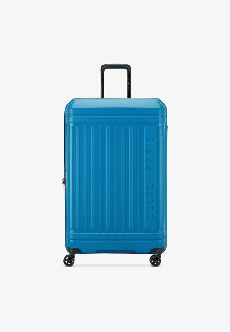 Maleta azul de carcasa dura con ranuras verticales, asa telescópica y cuatro ruedas. Presenta un logo de Delsey Paris en la parte frontal.