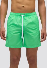 Costume da bagno verde brillante realizzato in materiale lucido e leggero. Presenta una vita con coulisse e dettagli bianchi, e tasche laterali.