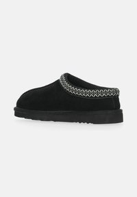 Sorte ruskinds slip-on sko med en polstret krave og dekorativ hvid syning langs den øverste kant. Har en flad, tekstureret gummisål.