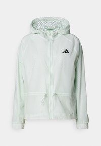 Chaqueta de cierre zip verde claro con capucha, con tela perforada, puños elásticos y cordones ajustables en la cintura. Logo negro en el pecho.