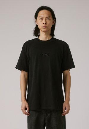 Black cotton t-shirt with short sleeves and a crew neckline. Centered embroidered text "FORMER" in a subtle finish. Relaxed fit, crew neck.