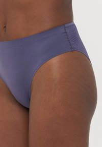 Hoog uitgesneden bikini onderkant in een gedempte paarse stof met een gladde afwerking, kenmerken een gestructureerd zijpaneel en gestikte randen.