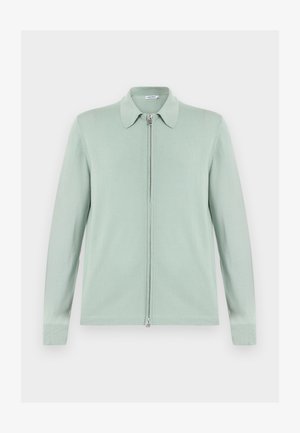 Svetlo zelena jopica z zadrgo, z dolgimi rokavi in ostrim ovratnikom, prikazana položeno na belem ozadju.