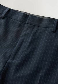 Pantalon bleu marine à fines rayures avec passants pour ceinture et fermeture éclair devant, présenté à plat sur une surface claire.