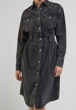 Vestido de mezclilla gris oscuro con botones, mangas largas, bolsillos en el pecho y cinturilla elástica, usado por una persona de pie sobre un fondo liso.