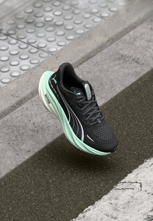 Black running shoe with a mesh upper and reflective details, featuring a mint green midsole and side accents, positioned above a textured surface.