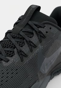 Czarne buty Nike Pegasus Trail 5 z teksturowaną siateczką, odblaskowymi akcentami i smukłym wzornictwem, które wyróżnia się wyraźnymi sznurówkami i detalami marki.