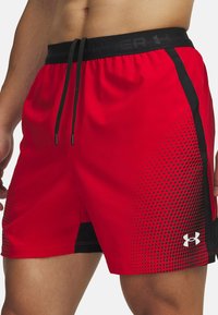 Pantalones cortos deportivos rojos con una cinturilla negra, que presentan un cordón y un patrón de puntos en un lado. Fabricados con un material ligero y transpirable.
