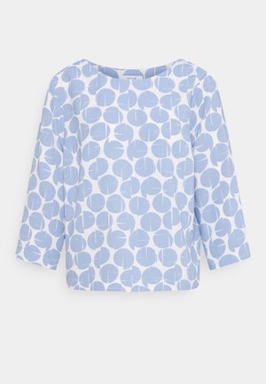 Jasnoniebieska bluzka z okrągłym wzorem w różnych rozmiarach, z rękawami o długości trzech ćwiartek i okrągłym dekoltem. Wykonana z miękkiego, teksturowanego materiału.