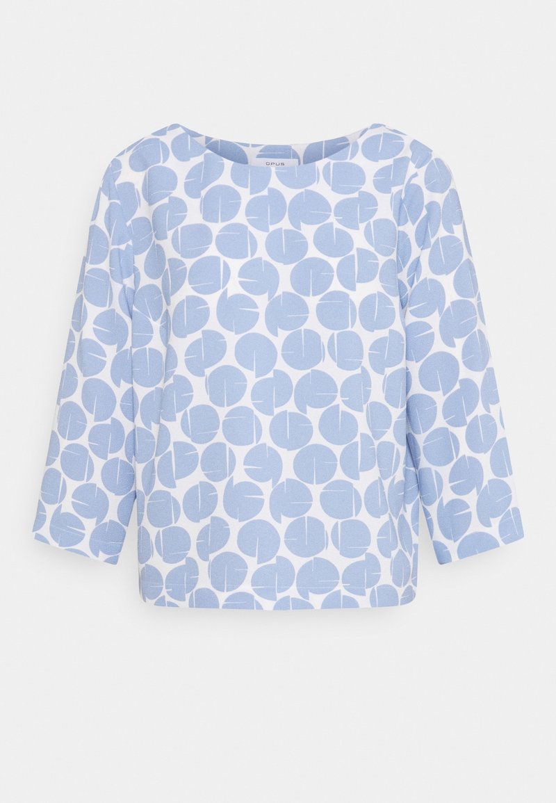Haut bleu clair avec un motif circulaire de tailles variées, manches trois-quarts et encolure arrondie. Fabriqué en tissu doux et texturé.