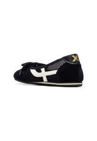 Zapato de ante negro y malla con un diseño de cruz blanca, puntera redondeada y un detalle de cuero negro en el talón con un logo dorado.