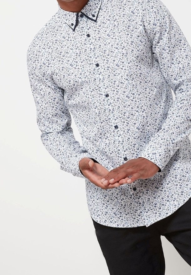 Langärmliges Hemd mit Knöpfen in Weiß mit blauem Blumenmuster und kontrastierendem schwarzem Kragen. Glatte Textur und tailliertes Design.