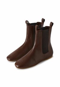 Botas de tobillo de cuero marrón con un acabado suave, paneles laterales elásticos y lengüetas en la parte superior para facilitar el calzado. Suela plana.