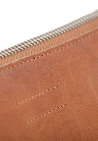 Portafoglio in pelle marrone con superficie texturizzata, dotato di una cerniera argentata e dettagli di cucitura sottili lungo i bordi.