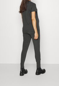 Grå bomull t-shirt med korta ärmar, kombinerad med mörkgrå tajta joggers och svarta kängor med kraftig sula. Enkelt mönster, mjuk känsla.