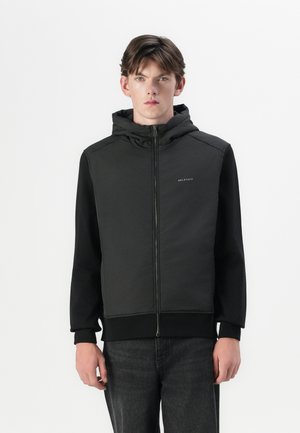Black zip-up jacket with a hood; features a smooth exterior, ribbed cuffs, and a logo on the left chest; paired with dark jeans.