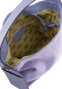 Lilla suede håndtaske med en blød tekstur og en bred åbning. Indersiden er foret med beige stof, der har et gentagende logomønster.