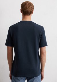 Navyblauwe T-shirt met korte mouwen, gemaakt van katoen, met een ronde hals en een rechthoekig label aan de achterkant van de hals. Glad textuur.