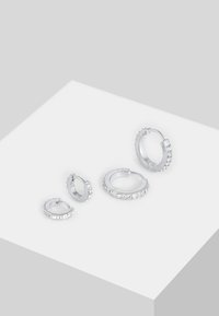 Orecchini a cerchio in argento con gemstone trasparenti, che presentano due paia più grandi e due più piccoli, variando nel design con una finitura lucida.
