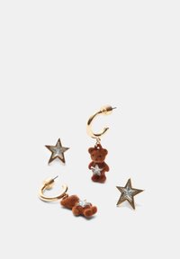 Guldtonede hoops med en brun bjørn charm og glitrende stjerner. Bjerget har en stjerneaccent; den bløde tekstur står i kontrast til metalfinishen.