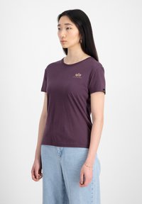 Lilla kortærmet t-shirt lavet af blød bomuld. Har en rund halsudskæring og et lille logo på brystet. Sættes sammen med lyseblå denim.