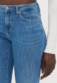 Hög midja blå denimjeans med en slät yta, utrustad med en framficka, klassisk sömnad och en knappstängning i midjan.