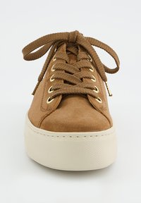 Baskets en daim marron avec lacets plats, œillets dorés et une semelle en caoutchouc blanc texturé ; présente un bout arrondi et des accents de design minimalistes.