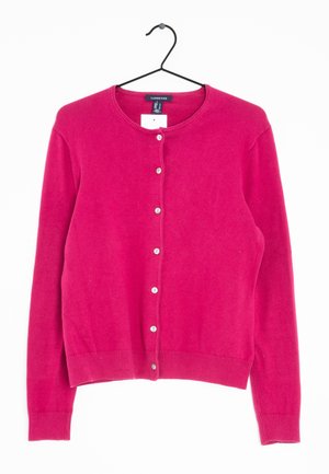 Jasnoróżowy kardigan zapinany na guziki z długimi rękawami, z prążkowanymi mankietami i dołem, wiszący na czarnym wieszaku na białym tle.