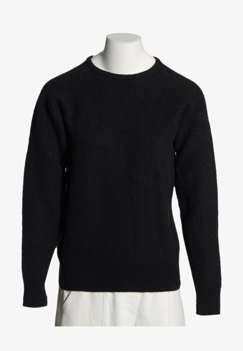 Pull noir à manches longues et col rond, présenté sur un torse de mannequin blanc avec un pantalon beige visible en bas.