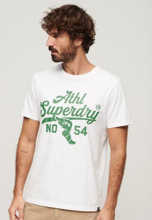 Camiseta de algodón blanca con texto gráfico verde "Athl Superdry JPN NO 54" en la parte delantera, mangas cortas y diseño de cuello redondo.