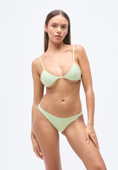 Σετ μαγιό σε ανοιχτό πράσινο με λεπτές ρυθμιζόμενες τιράντες· τριγωνικό τοπ και σλιπ χαμηλής μέσης· λεία υφή· μίνιμαλ σχεδιασμός χωρίς σχέδια ή μεταλλικά στοιχεία.