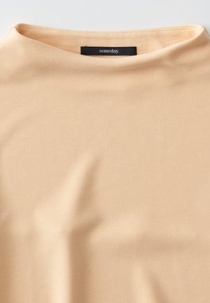 Licht perzikkleurig top gemaakt van een gladde stof met een hoge hals en korte mouwen. Voorzien van een zwart label met de tekst "someday."