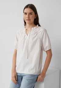 Jasno paskowana bluzka z miękkiego materiału z dekoltem w serek, marszczonymi falbanami przy ramionach, krótkimi bufiastymi rękawami i luźnym krojem.