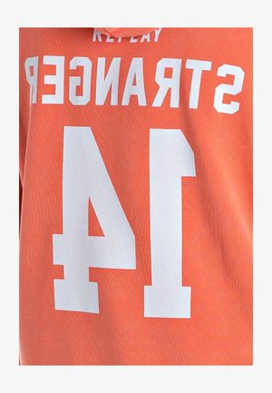 Sudadera color coral-naranja con gran texto blanco "STRANGER" y "14" en el frente. Confeccionada con una tela suave y texturizada.