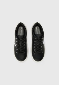 Black leather sneakers with white soles, featuring black laces, a logo on the tongue, and a white accent on the side.