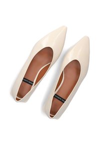 Beige patentslederen ballerina's met een spitse neus en uitsneden aan de zijkant, met een bruine binnenzool en een zwart merklabel aan de binnenkant.