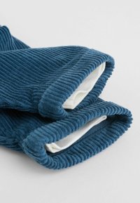 Guantes de canalé azul, hechos de suave tela de corduroy, con forro interior blanco y puños enrollados para mayor comodidad.